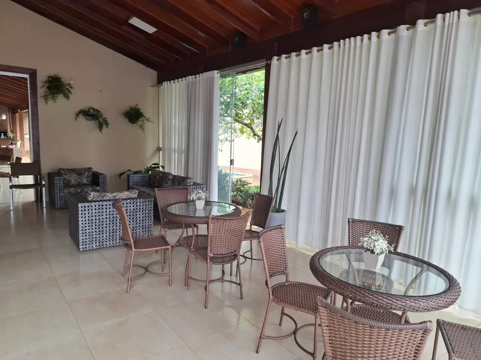 Área de convivência iluminada, com mesas e poltronas no Residencial Bem Estar